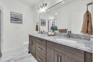 Full bathroom featuring a stall shower, marble finish floor, a sink, and baseboards