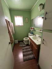 Bathroom with hardwood / wood-style floors, vanity, toilet, and ornamental molding