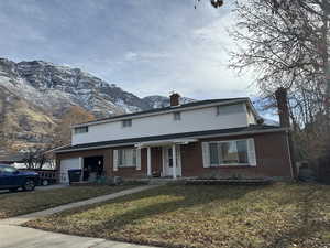 Front of property featuring a mountain view, a front lawn, and a garage