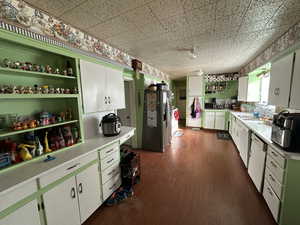 Kitchen with dishwashing machine, sink, white cabinetry, and stainless steel refrigerator with ice dispenser