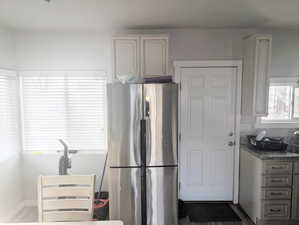 Kitchen featuring hardwood / wood-style floors, stainless steel fridge, and dark stone counters