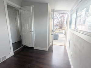 Corridor featuring a textured ceiling, dark hardwood / wood-style floors, and vaulted ceiling