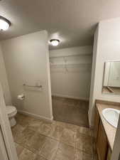 Bathroom with vanity, toilet, and a textured ceiling