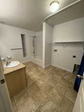 Bathroom with vanity, bathtub / shower combination, a textured ceiling, and tile patterned flooring