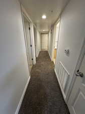 Hallway featuring dark colored carpet