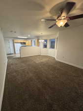 Unfurnished living room with ceiling fan with notable chandelier, light colored carpet, and a textured ceiling