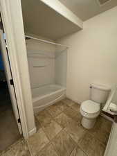 Bathroom featuring washtub / shower combination, a textured ceiling, and toilet