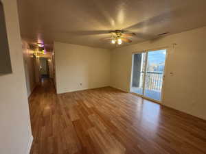 Empty room with ceiling fan, wood-type flooring, and a textured ceiling