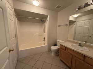 Full bathroom with toilet, tile patterned floors, a textured ceiling, shower / bathtub combination, and vanity