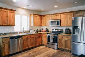 Kitchen featuring light stone countertops, stainless steel appliances, light hardwood / wood-style flooring, and sink