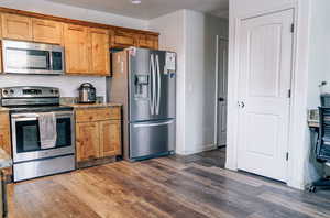 Kitchen featuring light stone countertops, stainless steel appliances, and dark hardwood / wood-style floors