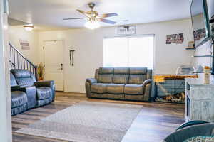 Living room with dark hardwood / wood-style flooring and ceiling fan