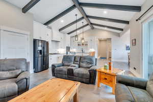 Living room with sink, light tile patterned floors, and lofted ceiling with beams