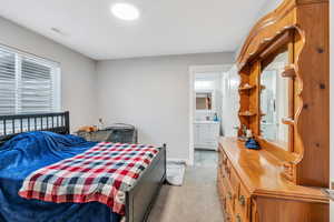 Bedroom with light carpet and ensuite bath