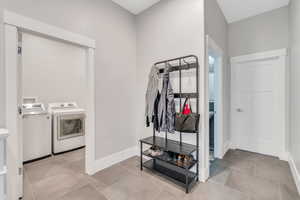 Clothes washing area featuring light tile patterned flooring and separate washer and dryer