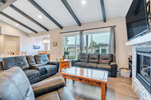 Living room with a stone fireplace and lofted ceiling with beams