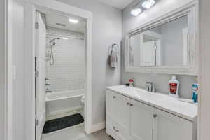 Full bathroom with tile patterned floors, vanity, tiled shower / bath combo, and toilet