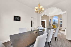 Carpeted dining space featuring a notable chandelier