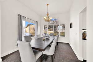 Dining space featuring dark colored carpet and an inviting chandelier