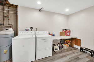 Laundry area with separate washer and dryer and hardwood / wood-style floors