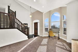 Entrance foyer featuring high vaulted ceiling and dark carpet