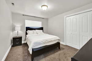 Carpeted bedroom featuring a textured ceiling and a closet