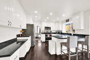 Kitchen featuring a breakfast bar, appliances with stainless steel finishes, white cabinetry, and sink