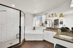 Bathroom with vanity, separate shower and tub, and a textured ceiling