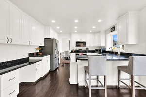 Kitchen with white cabinetry, sink, dark hardwood / wood-style floors, a breakfast bar area, and appliances with stainless steel finishes