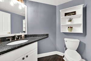 Bathroom featuring a textured ceiling, vanity, hardwood / wood-style flooring, and toilet