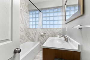 Bathroom with shower / bath combination with curtain, tile walls, and vanity