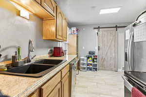 Kitchen featuring a barn door, sink, and stainless steel appliances