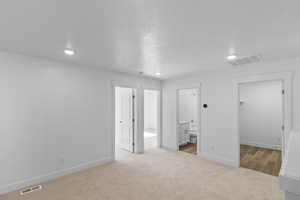 Loft area featuring connected bathroom, light colored carpet, and laundry room