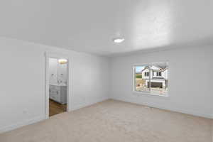 Primary bedroom with light carpet, ensuite bath, and dual sink