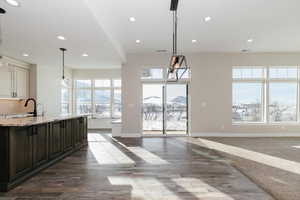 Kitchen with dark brown cabinetry, white cabinetry, light stone countertops, hanging light fixtures, and a mountain view