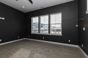 Carpeted empty room with a mountain view and ceiling fan