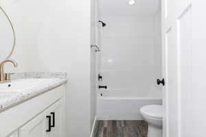 Full bathroom with vanity, toilet, wood-type flooring, and tub / shower combination