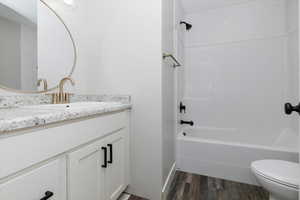 Full bathroom featuring shower / bathing tub combination, vanity, wood-type flooring, and toilet