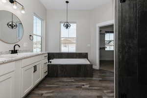 Bathroom featuring hardwood / wood-style floors, vanity, and tiled tub