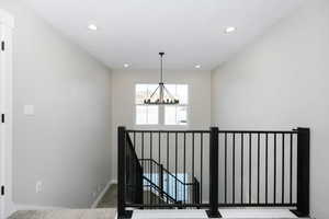 Staircase with carpet floors and a notable chandelier