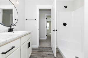 Bathroom featuring vanity, wood-type flooring, and walk in shower