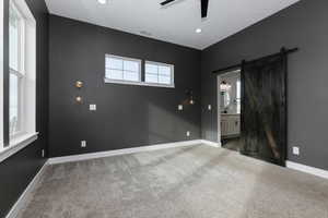 Carpeted spare room featuring ceiling fan, a barn door, and sink