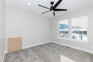 Empty room featuring a mountain view, ceiling fan, and light colored carpet