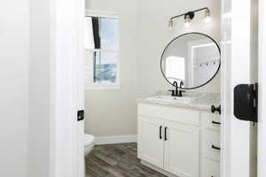 Bathroom with hardwood / wood-style floors, vanity, and toilet