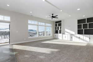 Unfurnished living room with a mountain view, carpet, and ceiling fan