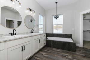 Bathroom featuring tiled bath, hardwood / wood-style floors, and vanity