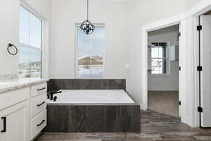 Bathroom with vanity, a relaxing tiled tub, and a healthy amount of sunlight