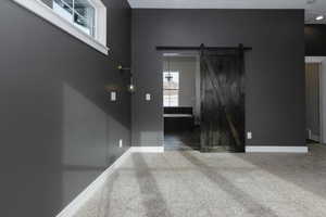 Carpeted spare room featuring a barn door