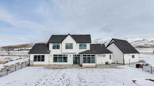 Snow covered back of property with a mountain view and central AC unit