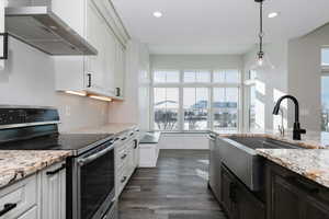 Kitchen with white cabinets, appliances with stainless steel finishes, and wall chimney exhaust hood